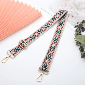 Close-up of geometric ethnic pattern on wide canvas shoulder strap with gold metal hooks