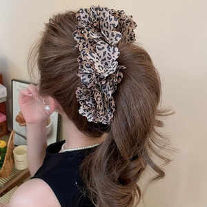 Detail of leopard print fabric flower hair clip styled on a low ponytail hair bun