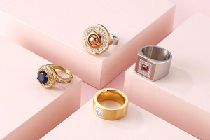 Detailed view of stainless steel rings with colorful zircon inlays on pink display