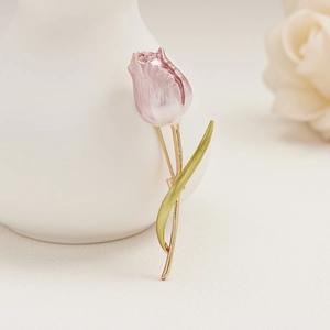 Close-up of pink tulip brooch with enamel petals leaning against a white ceramic vase