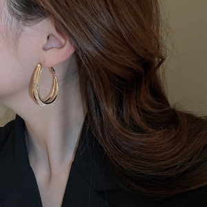 Close-up of gold double hoop earrings with cubic zirconia pavé on a female model