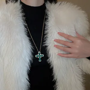 Collier croix en or raffiné avec des pierres de zircon vert émeraude sur un modèle