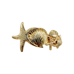 Detailed close-up of golden alloy hair clip featuring textured starfish and seashell motifs