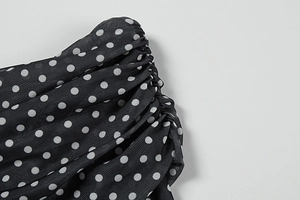 Close-up of black mesh fabric with white polka dots and elegant ruched texture details
