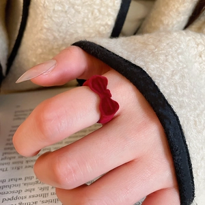 Close-up of a vintage red velvet bow ring worn on index finger with cozy winter vibes