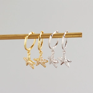 Macro detail of gold and silver S925 sterling silver starfish hoop earrings with zircon