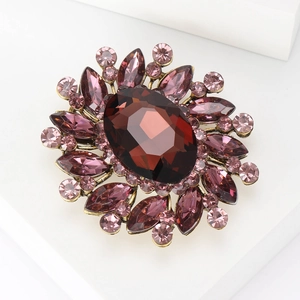 Close-up of vintage gold brooch with large purple oval crystal and teardrop gems