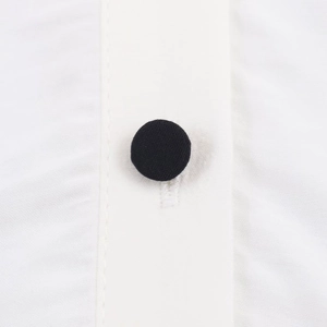 Detail of a black fabric-covered round button on high-density white woven shirt fabric