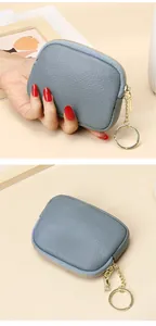 Macro detail of blue pebble leather mini wallet featuring gold zipper and keychain ring