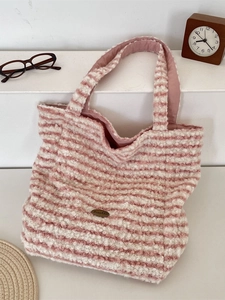 Plush pink striped double-sided tote bag with soft faux shearling texture on white shelf