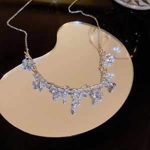 Macro shot of silver branch vine necklace with water drop crystals on a mirrored base