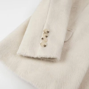 Detailed close-up of cream fuzzy fleece coat texture with amber tortoiseshell buttons