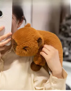 Close-up of soft plush capybara toy with black stitch details on a warm model shoulder
