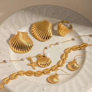 Golden ocean theme jewelry set with starfish and seashell charms on a ceramic plate
