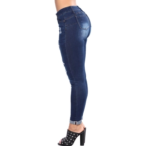 Detail view of distressed blue slim fit denim jeans with ripped holes and lifting effect