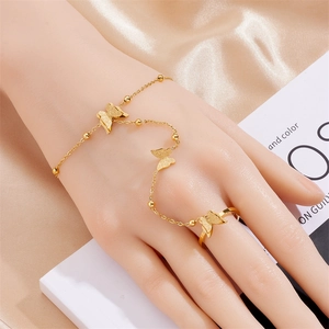 Detail of gold butterfly hand chain ring with elegant matte texture on silk fabric