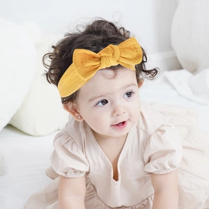 Cute yellow baby headband with soft fabric bow on a sleeping infant model