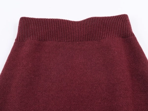 Gros plan d'une jupe midi en maille bordeaux avec texture côtelée sur fond blanc neutre
