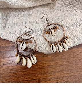 Detail of bohemian shell tassel earrings with bronze metal hoops and natural wood beads