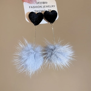 Dettaglio di orecchini a cuore con pompon grigi e perni in argento S925 tenuti in mano
