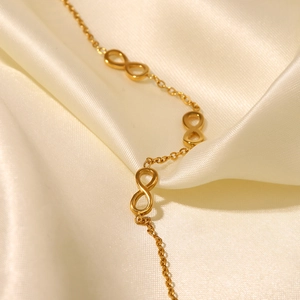 Macro detail of 18K gold plated infinity link chain on white silk background