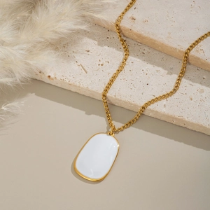 Dettaglio di una collana bohémien dorata con pendente ovale bianco su una pietra strutturata