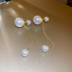 Detail of elegant gold-plated drop earrings featuring cascading white pearls on fine chains