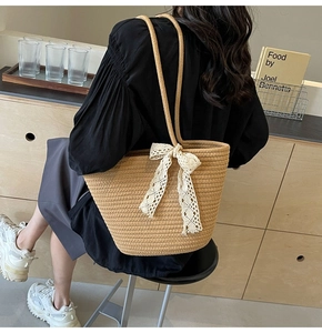 Detailed view of beige woven tote bag with white lace bow on indoor background