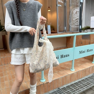 Detail of floral canvas tote bag with white lace bow accent in a lifestyle outdoor setting