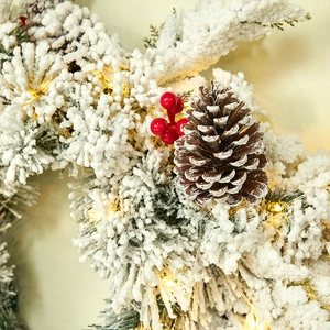 Christmas wreath with artificial pine, red berries, snowy flocking and warm LED lights