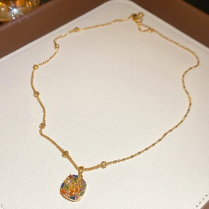 Detail view of gold-plated necklace with colorful zircon pendant on white leather box