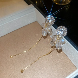 Macro shot of long gold tassel earrings with zircon studs and crystal petal details