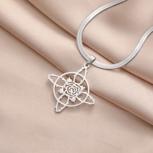 Détail du pendentif rose ajouré et de la chaîne serpent sur du tissu satiné rose