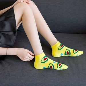 Bright yellow low-cut fruit socks with avocado print and ribbed cuff worn by model