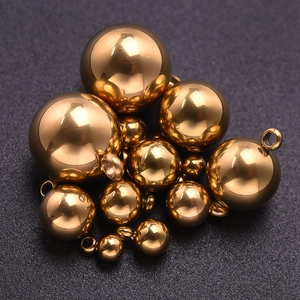 Gros plan de pendentifs boules en acier inoxydable doré poli de différentes tailles