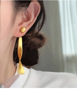 Close-up of model wearing golden matte brushed long spiral drop earrings with a stud