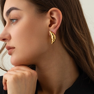 Close-up of golden croissant dome earrings on model showcasing 18k gold metallic luster