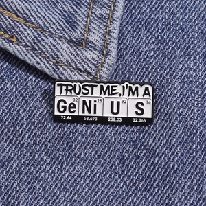 Detail of metal badge with GeNiUS chemical elements pinned on blue denim fabric
