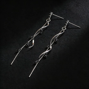 Detailed macro view of silver vine earrings featuring black oval gemstones and tassels