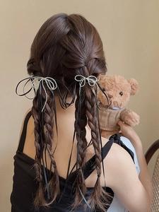 Detail of silver bow hair clip with black ribbon tassels on braided hairstyle