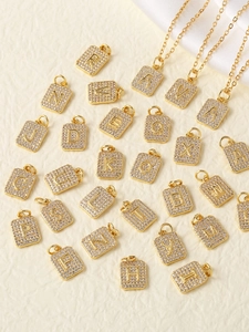 Flat lay of gold alphabet square pendants with zircon pavé setting and matching chains