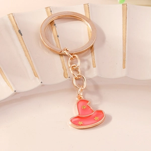 Close-up of pink enamel witch hat keychain with gold stars on white ceramic tray