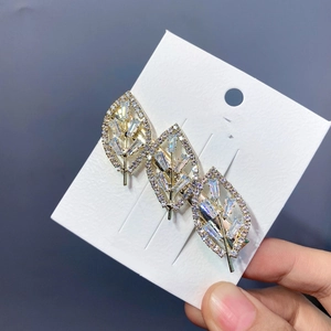 Macro detail of gold-plated leaf hair clip featuring sparkling inlaid cubic zirconia stones
