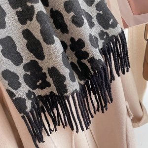 Detail shot of leopard print scarf with soft gray texture and black decorative fringe