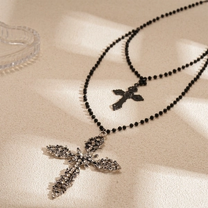 Detailed macro of a double-layered necklace with diamond-set cross and black beads