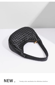 Detail of black woven leather hobo bag with gold triangle zipper on white geometric base