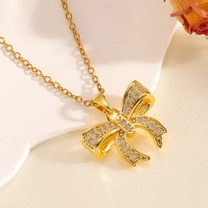 Close-up of golden bow necklace with inlaid rhinestones and shell on warm silk