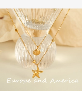 Close-up of double-layer gold necklace with starfish, seashell pendants and pearl detail