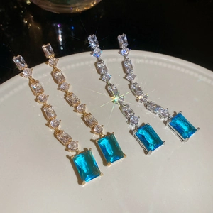 Detail of luxury long tassel earrings with blue rectangular zircon and gold plating