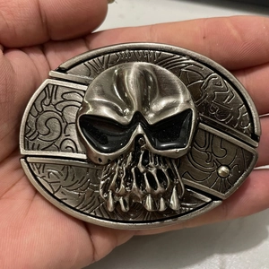 Detailed close-up of a vintage silver tiger head belt buckle with gothic carvings